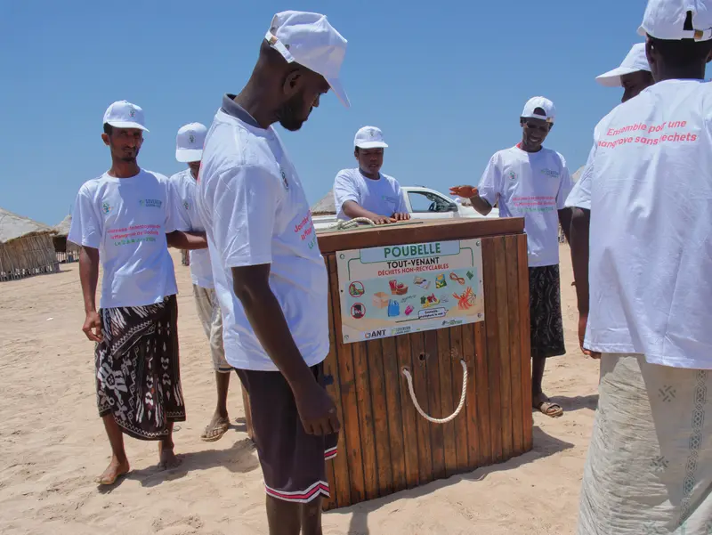 Groupe réuni autour d’un bac de tri sur la plage.